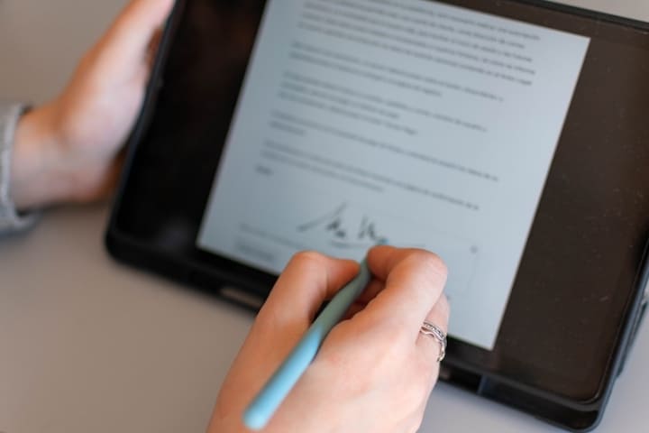 契約更新を表現する、タブレットで書類にサインする手