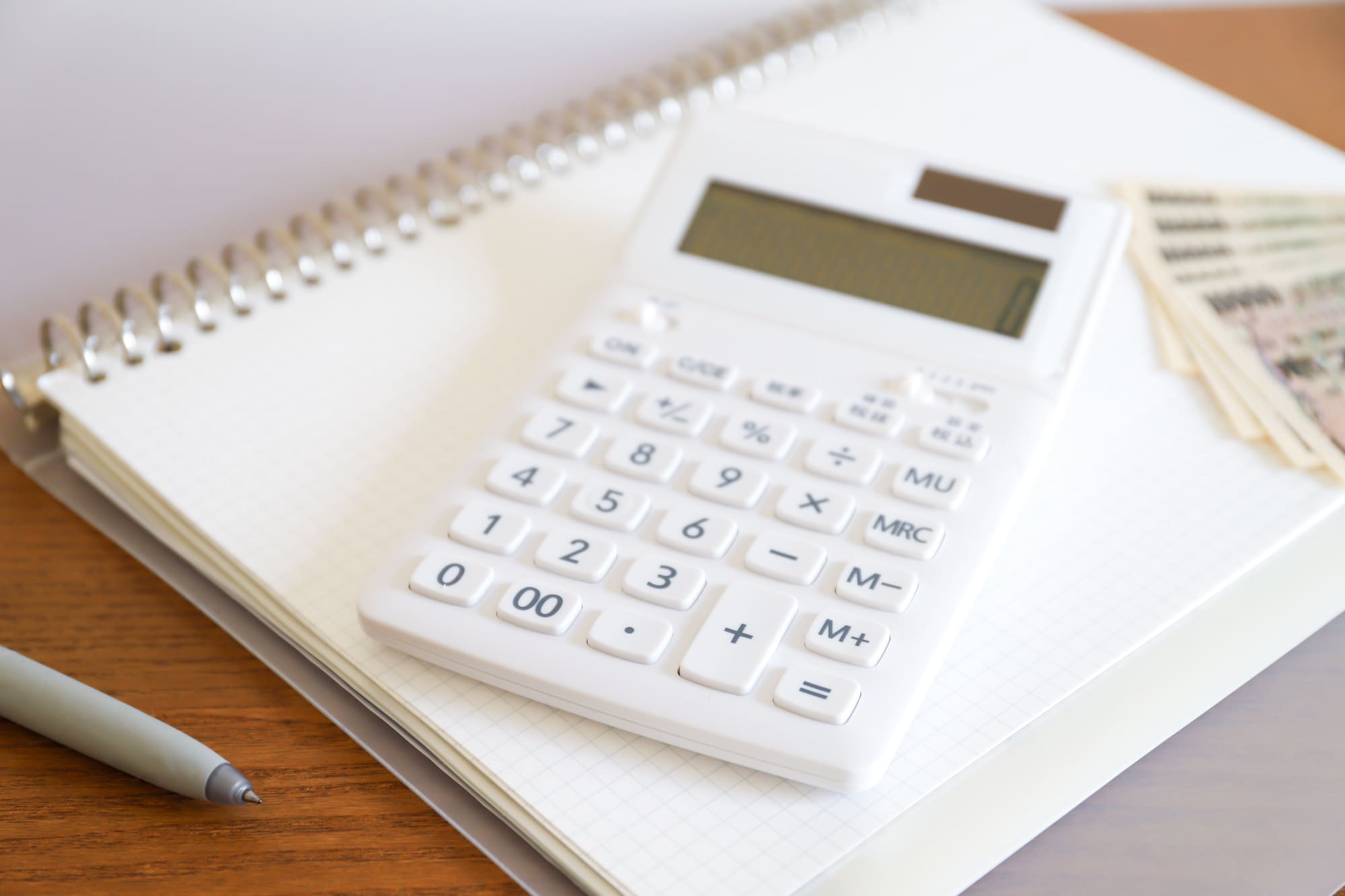 支払い計画を表現する、電卓と日本円紙幣が置かれたノート